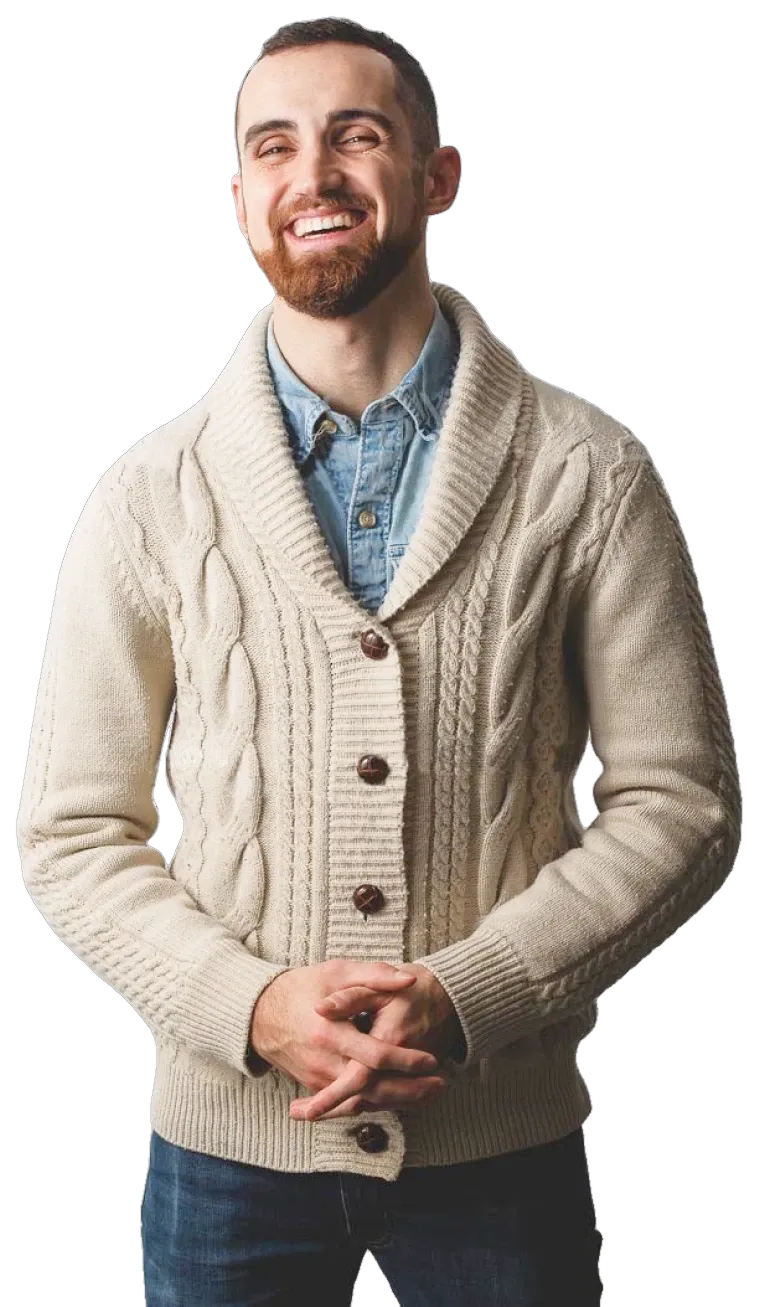 Tom Cobb, smiling, in a cream cable-knit cardigan